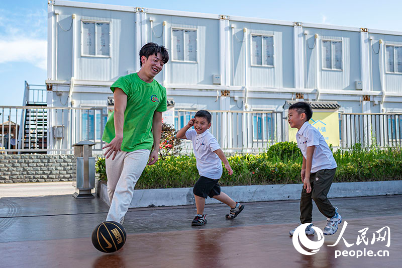 2024年7月24日，在上海临港新片区建设者小镇中建八局105社区，大学生志愿者带领爱心暑托班的小朋友们一起做游戏。上海市小学生爱心暑托班已连续11年被列入上海市为民办实事项目，切实帮助家长解决了孩子暑期“看护难”问题。人民网记者 王初摄